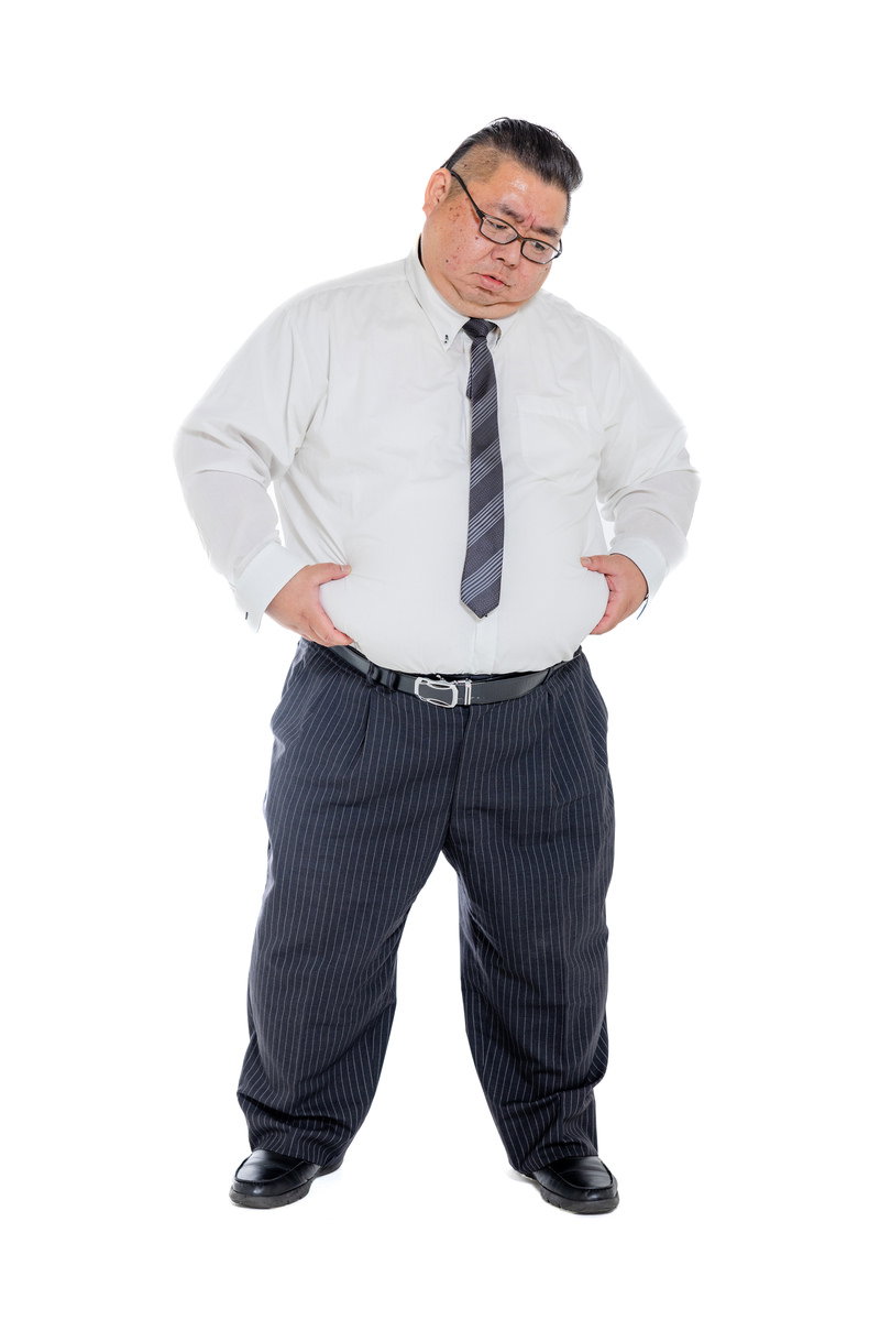 白いシャツと紺色のスーツを着た男性がお腹の脂肪を両手で抱えている［モデル：ダルマ親方］