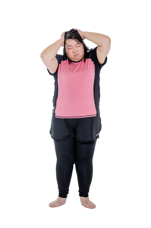 エクササイズ中に頭を抱えて悩む膨よかな女性