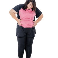 ウエストの贅肉を両手で摘まむエクササイズ前の女性の写真