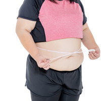ぽっちゃりしたお腹周りをメジャーで測定する女性の写真