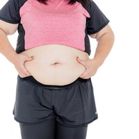 両手でお腹の贅肉を掴む女性の写真