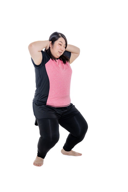 ピンクトップでスクワットしてダイエットに励む膨よかな女性