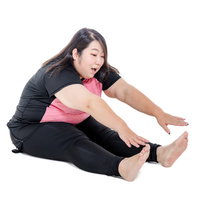 足の指に手が届かない前屈で膨よかな女性のストレッチの写真