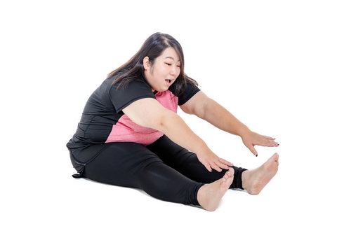 足の指に手が届かない前屈で膨よかな女性のストレッチ