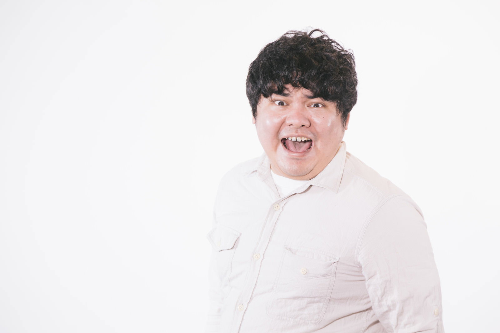 白いシャツを着た男性が大きく口を開けて叫んでいる［モデル：段田隼人］