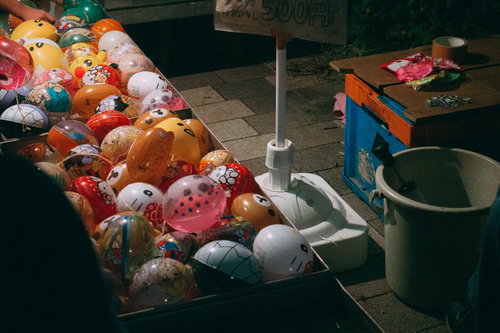 夏祭りの屋台で色とりどりのヨーヨー釣りを楽しむ子どもたち