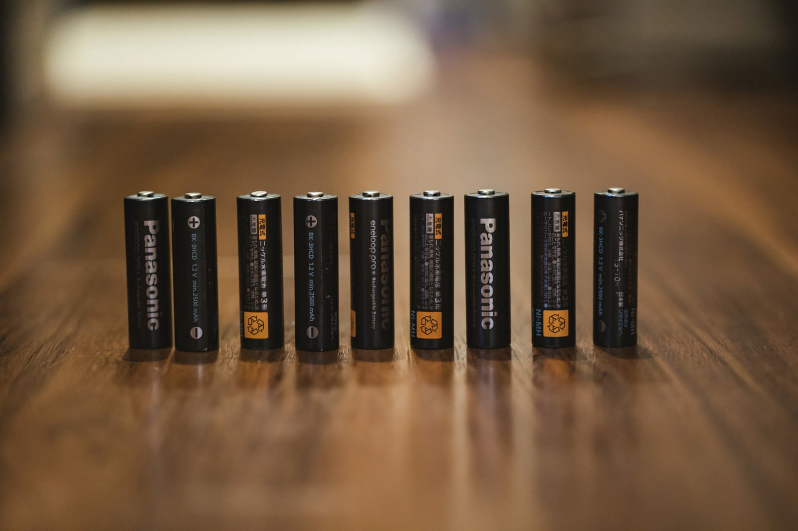 木製テーブルの上に整然と並べられた8本の黒い単三電池