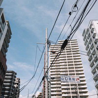 都市景観に張り巡らされた電線と高層マンションの写真