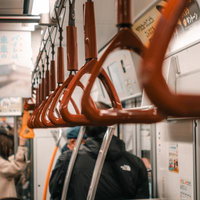 混雑する電車の車内と赤茶色の吊り革の写真