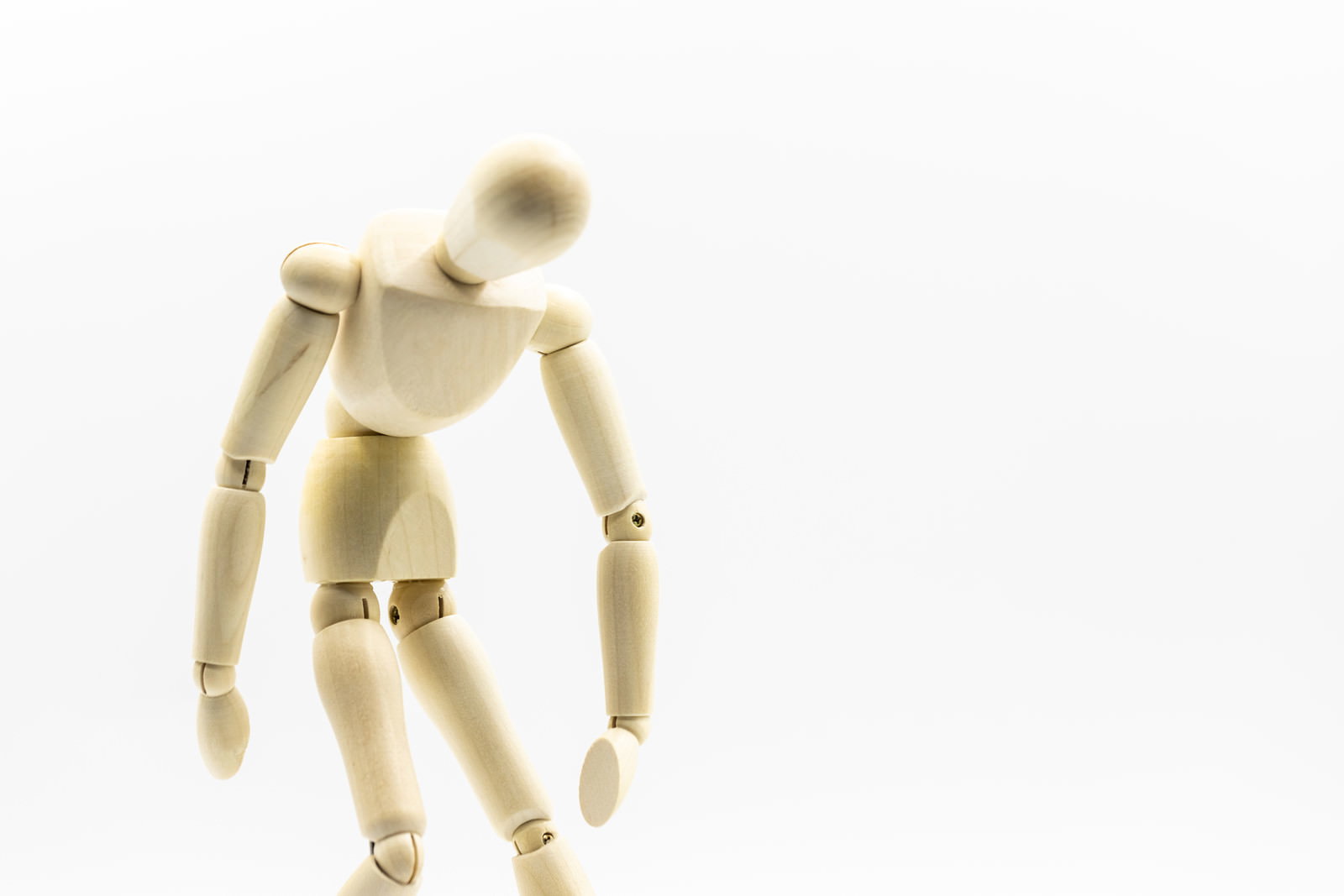 木製のデッサン人形が疲労で頭を垂れてぐったりと座り込んでいる