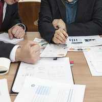 資料を広げて議論する打ち合わせ中の社員たちの写真