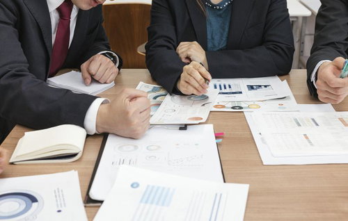 資料を広げて議論する打ち合わせ中の社員たち