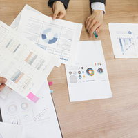 資料を手に取りオフィスで打ち合わせ会議をする複数人の写真