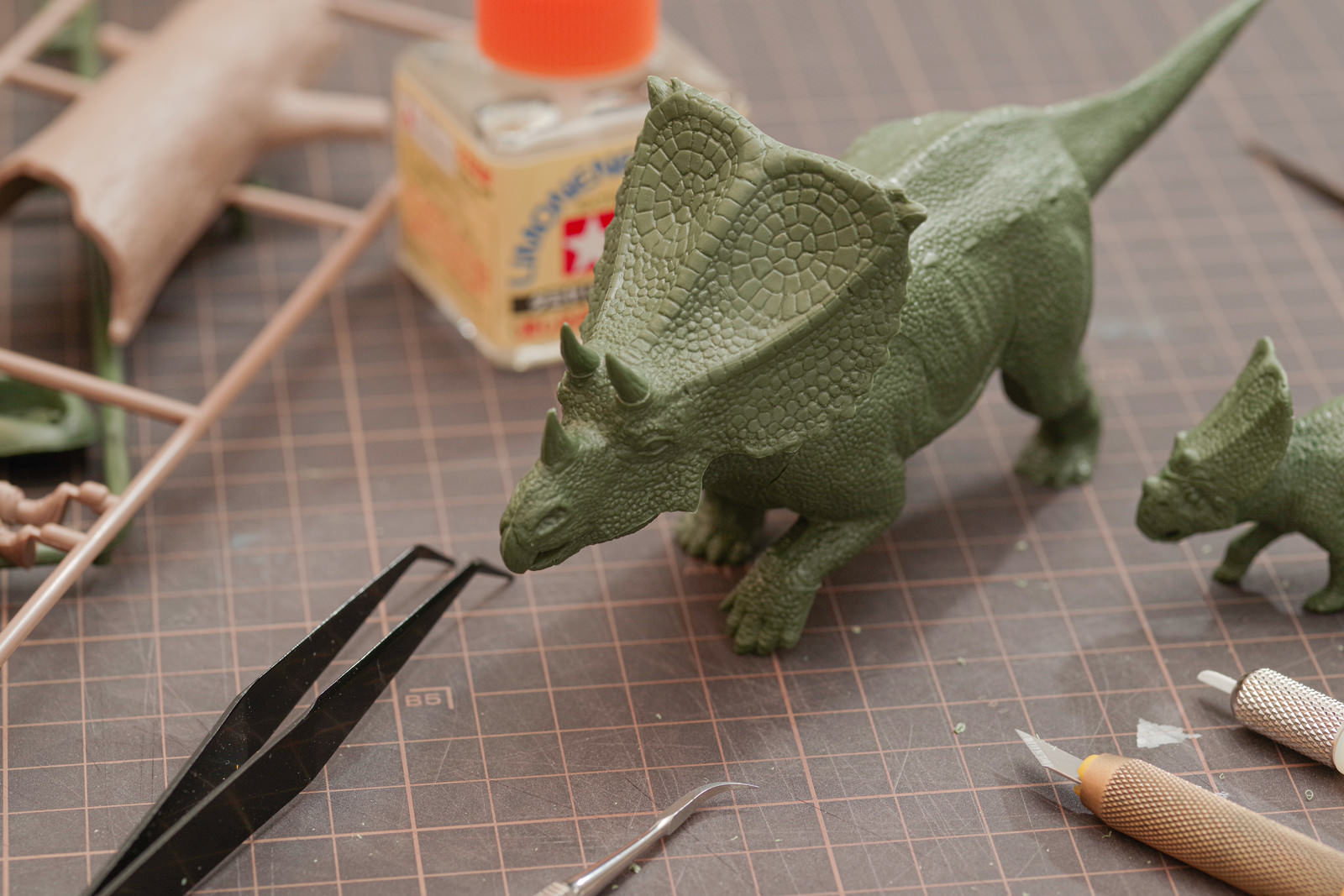 カッティングマットの上で恐竜のプラモデルを工作している様子
