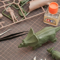 恐竜のプラモデルとパーツ類を工具で製作する様子の写真