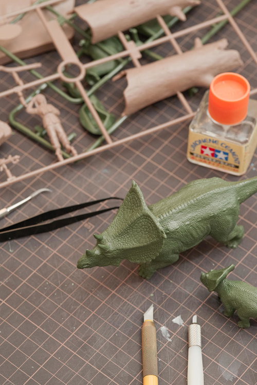 恐竜のプラモデルとパーツ類を工具で製作する様子