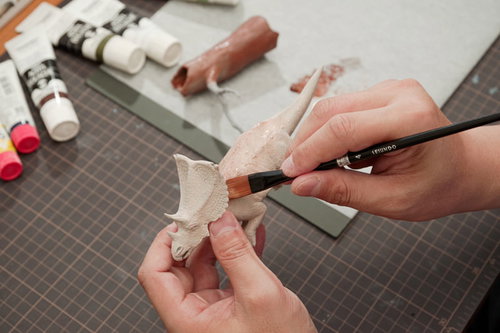 恐竜のプラモデルにベース色を塗装しているところ