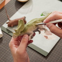 恐竜のプラモデルにドライブラシで泥汚れを塗装する手元の写真