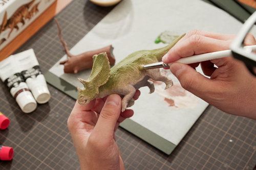 恐竜のプラモデルにドライブラシで泥汚れを塗装する手元