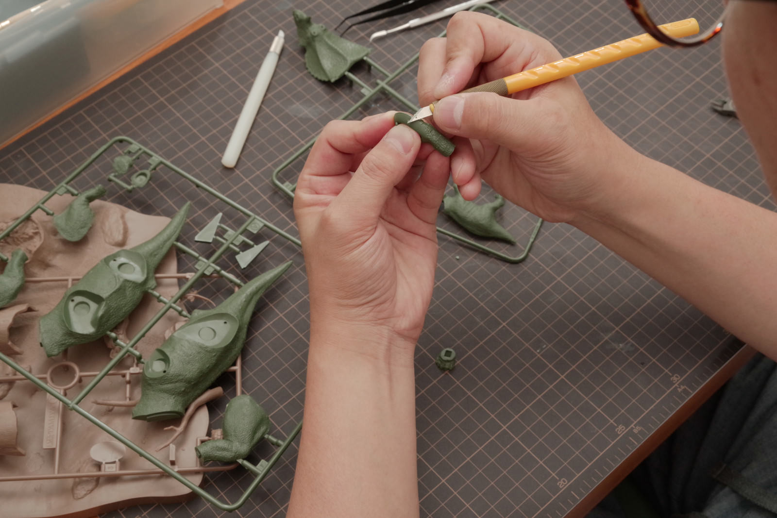 デザインナイフでプラモデルのパーツをゲート処理している手元