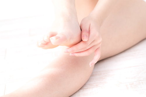 かかとを念入りにケアする色白な女性の手と足