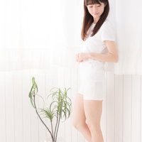 白いカーテンの前に立つ色白の女性のスキンケアの写真