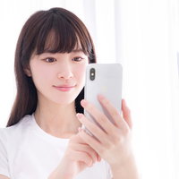 スマホでポチる白いTシャツの色白な女性のスキンケアの写真