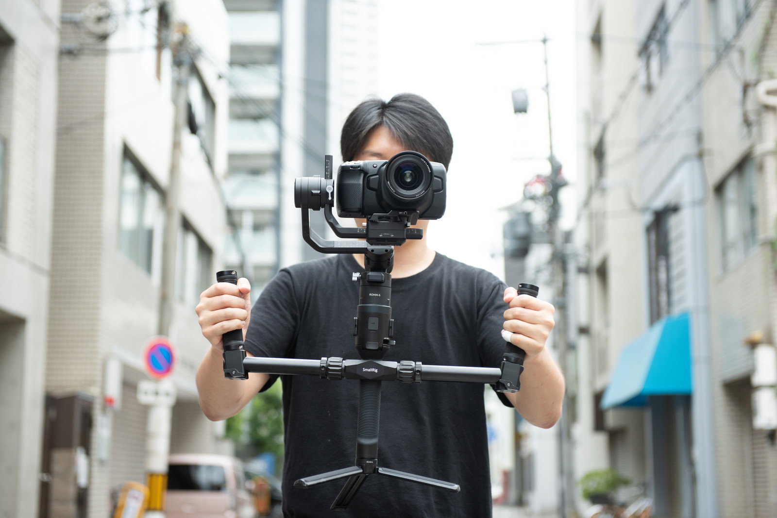 ジンバルを使って動画撮影をしている黒い服装の男性［モデル：瀧野恵太］