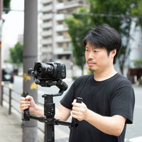 ジンバルを使って屋外で撮影する男性カメラマンの写真