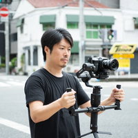 屋外でジンバルを使った動画撮影をする男性カメラマンの写真