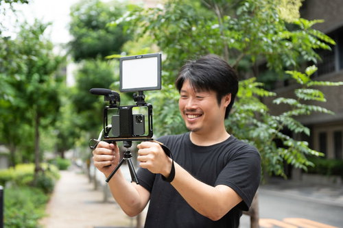 マイクとライトを装着したスマホで撮影を行う男性カメラマン