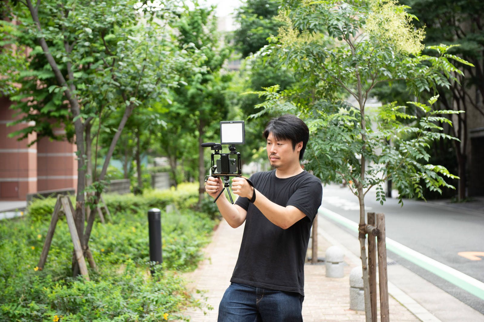 屋外でスマホリグを構えてムービー撮影する男性［モデル：瀧野恵太］