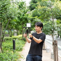 屋外でスマートフォンを使ってムービー撮影をする男性カメラマンの写真
