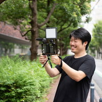 外付けマイクを装着したスマートフォンで動画撮影を楽しむ男性の写真