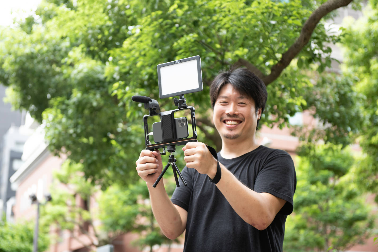 スマートフォンとマイクで動画撮影をする笑顔の男性カメラマン［モデル：瀧野恵太］