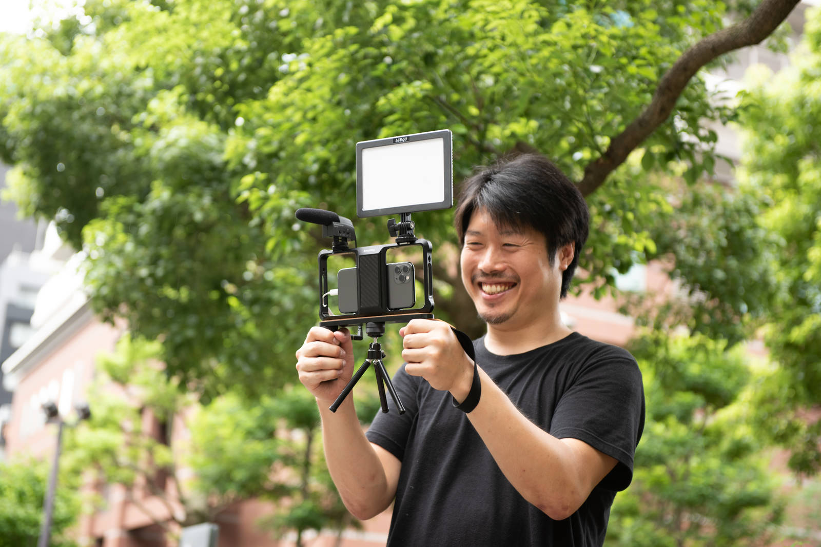 スマホにマイクを接続して動画撮影する黒いTシャツの男性カメラマン［モデル：瀧野恵太］