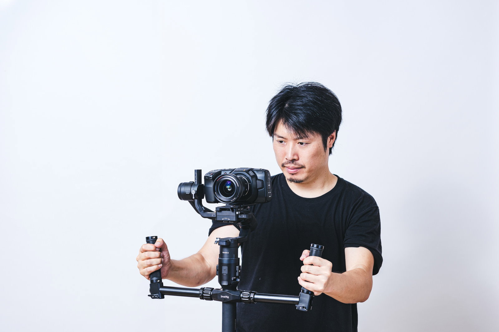 ジンバルに一眼カメラを乗せて撮影する黒いTシャツの男性［モデル：瀧野恵太］