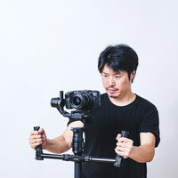一眼カメラをジンバルスタビライザーに乗せてムービーを撮影する男性の写真