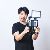 照明機材を取り付けたスマホでムービー撮影する男性の写真