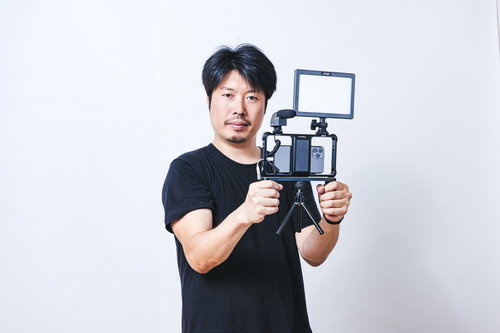 照明機材を取り付けたスマホでムービー撮影する男性