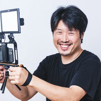 笑顔でスマホを使ってムービー撮影をする男性の写真