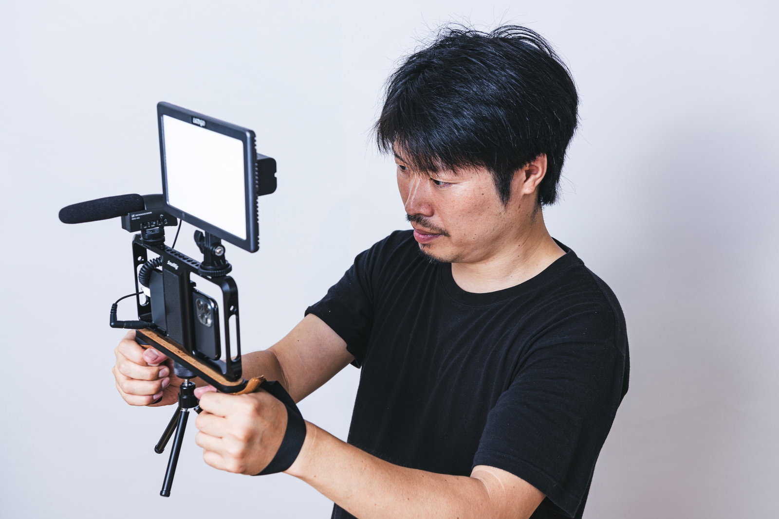照明機材を使ってスマホで動画撮影する黒いTシャツの男性カメラマン［モデル：瀧野恵太］