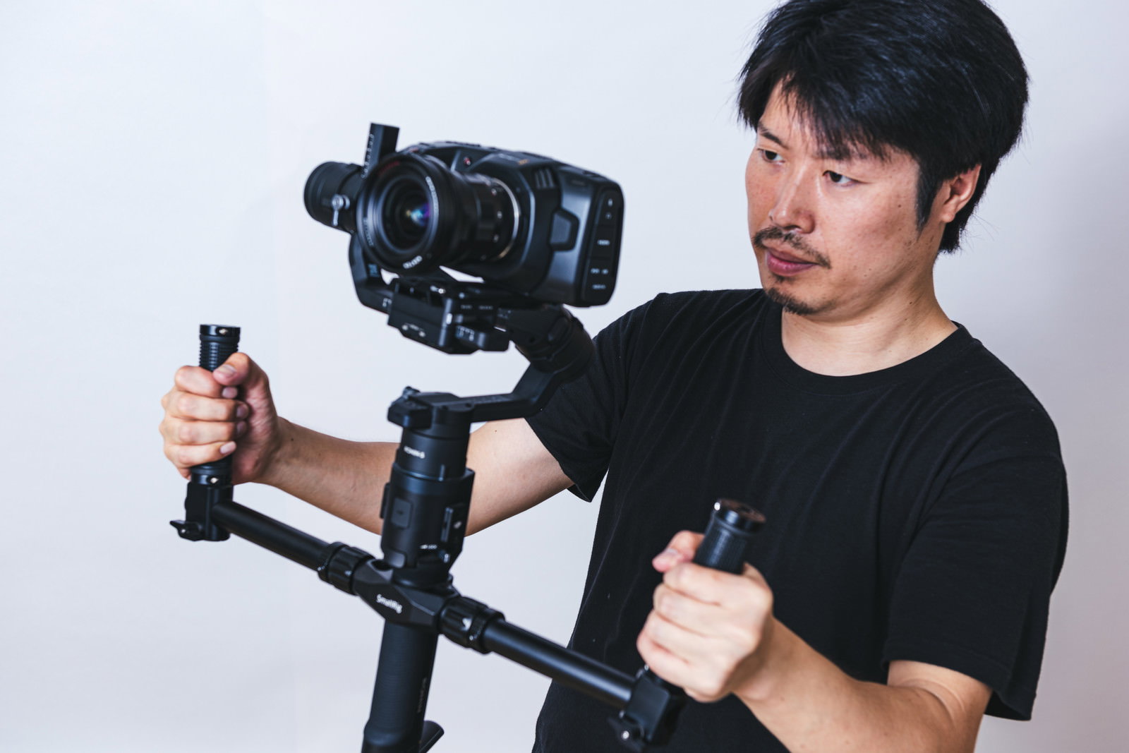 ジンバルに装着した一眼カメラで動画撮影をする黒いTシャツの男性［モデル：瀧野恵太］