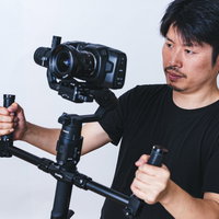 ジンバルで一眼カメラを構えて動画撮影する男性の写真