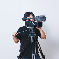 三脚に設置したビデオカメラで水平方向にパンをするカメラマンの写真