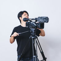 現場に指示を出す男性カメラマンとビデオカメラ機材の写真