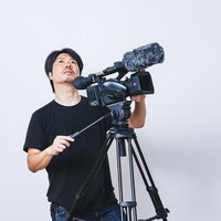 天候の変化を気にしながらムービー撮影を続けるカメラマンの写真