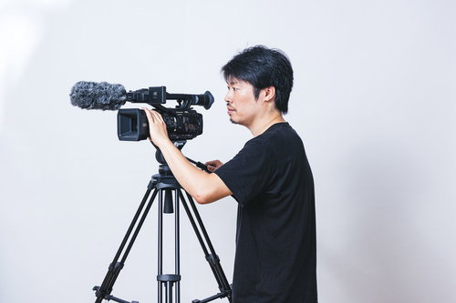 ビデオカメラのモニターを確認しながらフレーミングするカメラマン