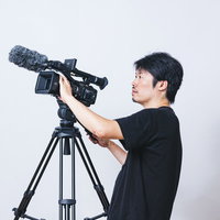 ビデオカメラ用の三脚に取り付けて撮影する男性カメラマンの写真