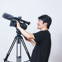 笑顔で被写体を追うビデオカメラマン、三脚で業務用カメラを操作の写真